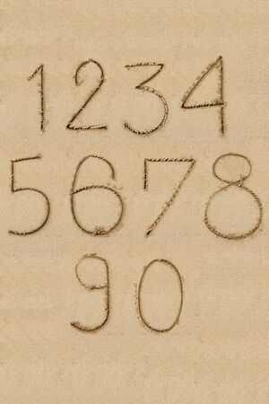 Numbers one to zero written on sandの写真素材