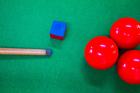 Snooker cue with chalk and ball on green table
