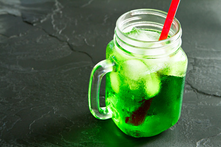 Jar of sweet drink with red straw on stone table.の写真素材