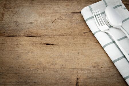 Silverware and napery on wooden background.