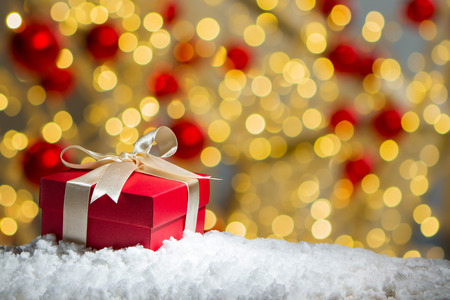 Red gift box on snow with abstact bokeh background.