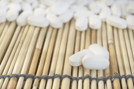 White pills on yellow bamboo mat