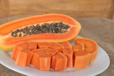 Papaya slice on white dish over grunge sack with wooden backgroundの写真素材