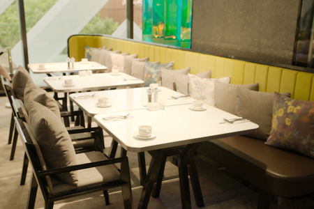 Abstract blurry restaurant with blurry green large tree visible outside windows in background