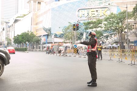 Bangkok, Thailand - January 14, 2015 Traffic police redirect car out of Pathumwan intersection during "Discover Thainess 2015" parade event with MBK shopping center in backgroundのeditorial素材
