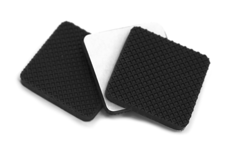 Anti scratch and slip rubbers with builtin adhesive over white background with one piece showing adhesive side cover by white thin sheetの写真素材