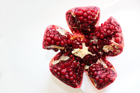 Cut ripe pomegranate into pieces on a white backgroundの写真素材