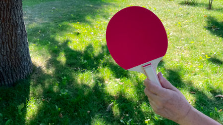 Female hand pensioner golden age holding table tennis racket in garden
