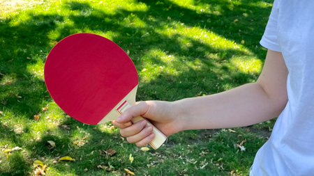 Young female hand holding tennis table racket in garden