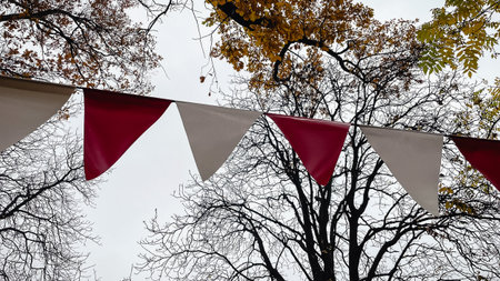 Red and white triangular bunting hanging against a background of bright yellow autumn foliage and...