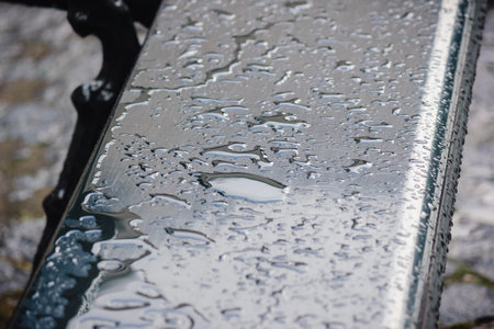 Close up of a dark, wet table surface covered in water puddles and rain with abstract patternsの写真素材