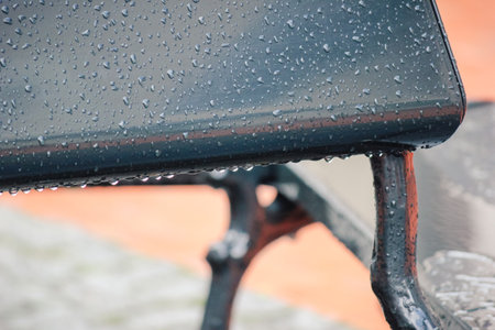 Close up of a dark, wet table surface covered in water puddles and rain with abstract patternsの写真素材