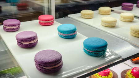 Assorted colorful French macarons in purple, blue, and white colors on a tray in a bakery displayの写真素材