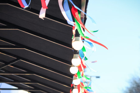 Spring festival canopy decorated with vibrant colorful ribbons and warm glowing light bulbs.