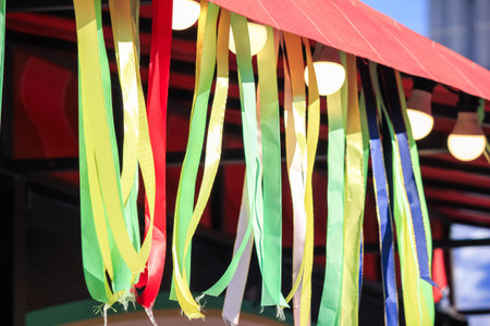 Spring festival canopy decorated with vibrant colorful ribbons and warm glowing light bulbs.