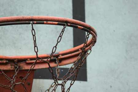Detailed close up of a weathered basketball hoop rim with a durable chain net against a backboard