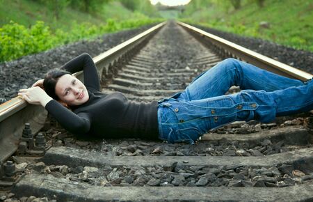 Young smiling girl lying on the railwayの写真素材