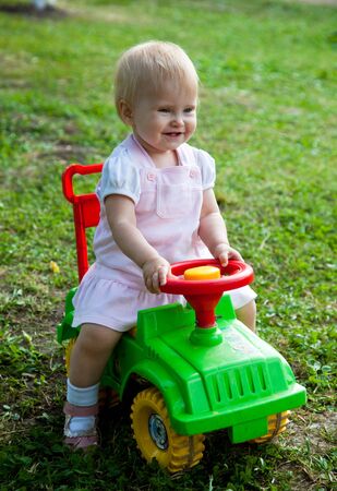 Little girl sitting on a green carの写真素材