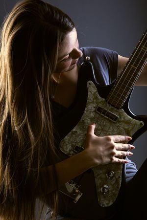 Woman with electric guitar on gray background