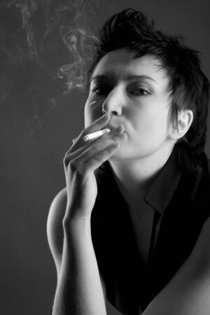 Beautiful young woman with a cigarette and smokeの写真素材