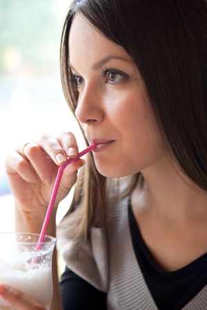 Young girl is drinking cocktail in cafeの写真素材