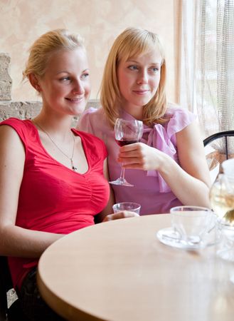 Two young girls are drinking wine in cafeの写真素材