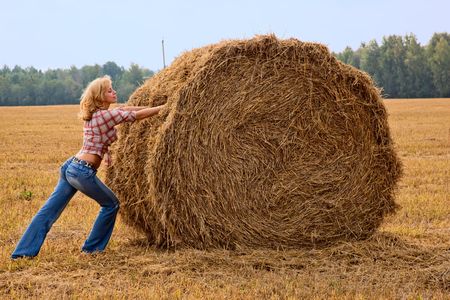 Young woman is pushing bale of strawの写真素材