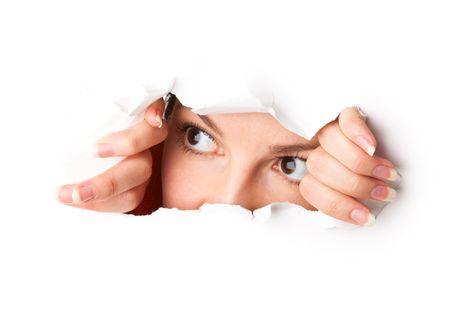 Eye looking through hole. Isolated on white backgroundの写真素材