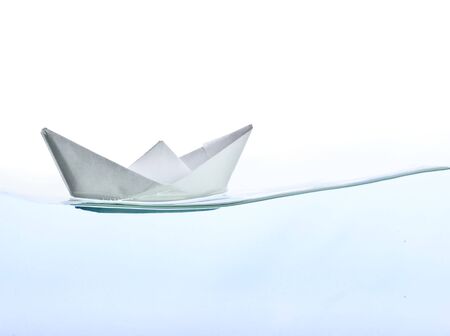 Origami boat on water. Isolated on white backgroundの写真素材