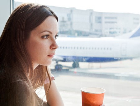 Young woman is drinking coffee in airportの写真素材