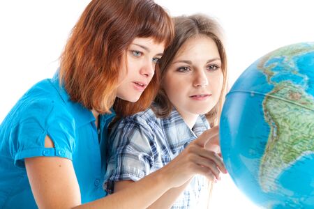 Two teen-girls are looking at globe. Isolated on white backgroundの写真素材