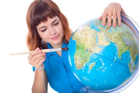 Red-haired girl is painting globe. Isolated on white backgroundの写真素材