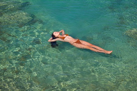 a young beautiful woman is swimming in a seaの写真素材