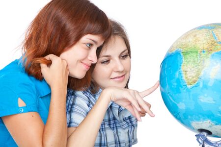 Two teen-girls are looking at globe. Isolated on white backgroundの写真素材