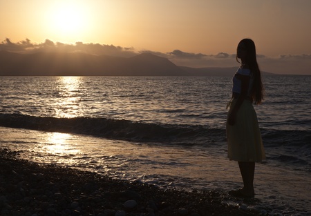 a young woman is looking at sunsetの写真素材