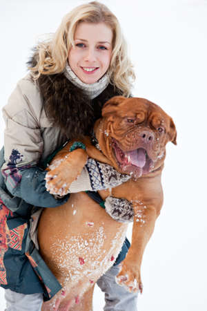 a smiling woman is sitting at the snow with her dogの写真素材