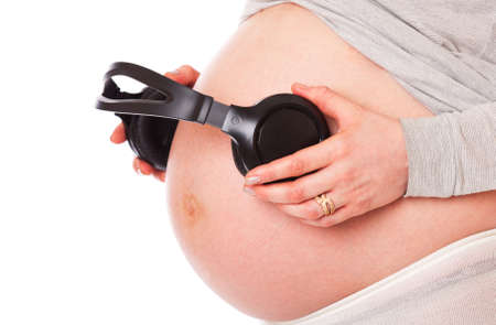 a belly of pregnant woman with headphones. isolated on a white background