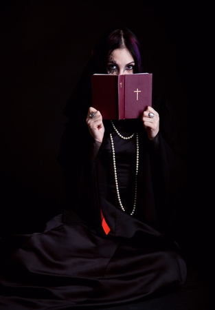 A gothic girl with the Bible. Isolated on a black bachgroundの写真素材