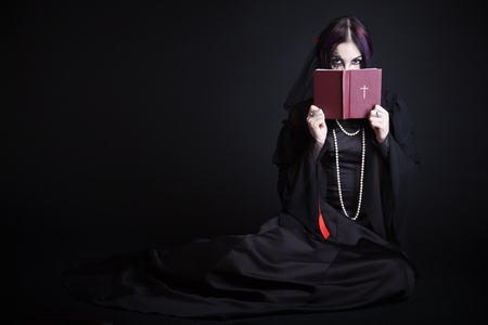 A gothic girl with the Bible. Isolated on a black bachgroundの写真素材