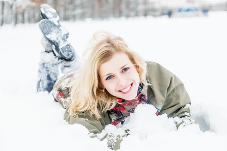 a beautiful woman is lying at the snow in the parkの写真素材