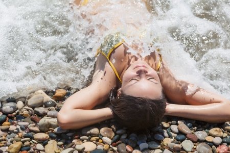 Young smiling woman is lying on the beachの写真素材