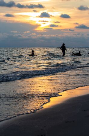 The silhouette of family enjoying activity on the beach at sunsetの写真素材