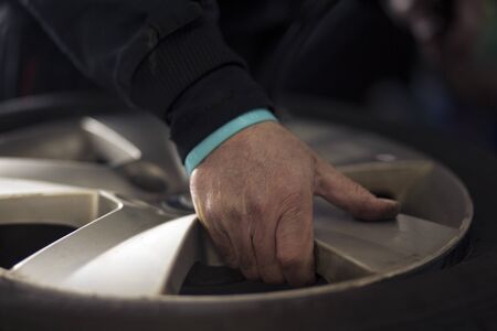 Preparing wheel for tire change because of winter season. Man hand.