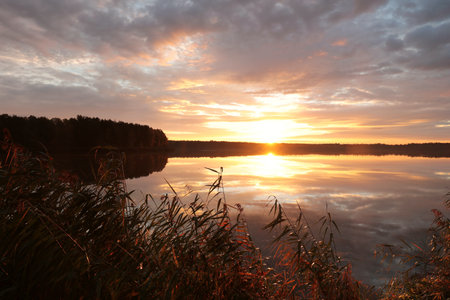Sunrise over the lake on a cloudy autumn dayの写真素材