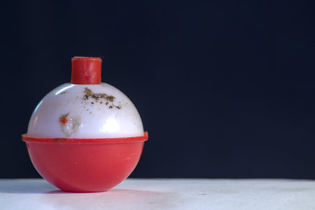 Close up of a red plastic fishing float isolated on black background.の写真素材
