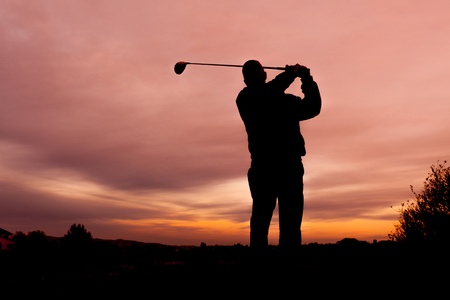 Golfer Silhouetted in Sunsetの写真素材