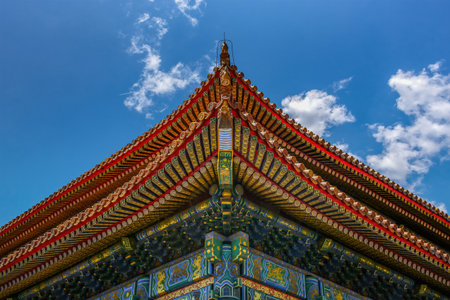 Close-up of ornate Forbidden City roof with colorful wooden eaves under blue sky, symbolizing classic Chinese imperial architecture.の写真素材