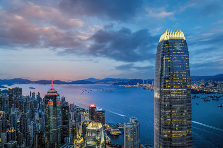 Hong Kong skyline at Victoria Harbor during blue hour with illuminated skyscrapers, boats and...