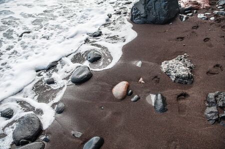 Footprints in the sand. Black sand on the Red Beach. Santorini island, Greeceの写真素材