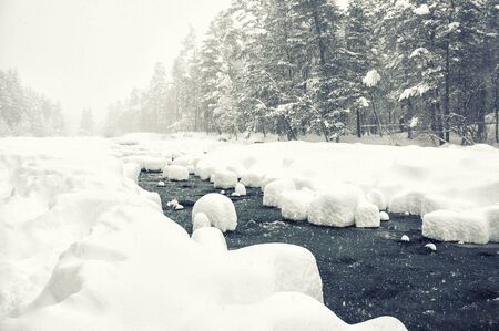 Snowfall on the mountain river. Beautiful winter landscape. Creative toning effectの写真素材